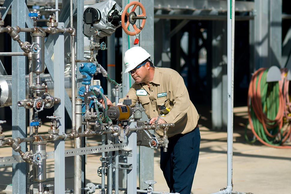 Operator wearing safety gear checking valves and gauges on a hydrogen plant